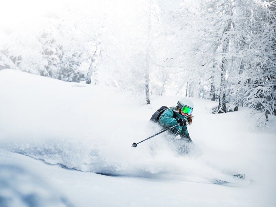 © Atomic Austria GmbH Skier carving through deep powder in a snowy forest. | © Atomic Austria GmbH