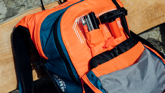 © Mammut Archive Open orange and blue backpack on a wooden bench. | © Mammut Archive