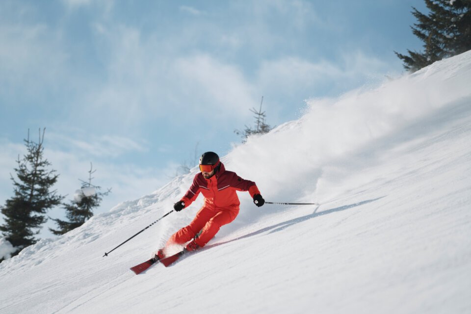 © INTERSPORT International Corporation GmbH Skieur en combinaison rouge dévalant une pente enneigée. | © INTERSPORT International Corporation GmbH