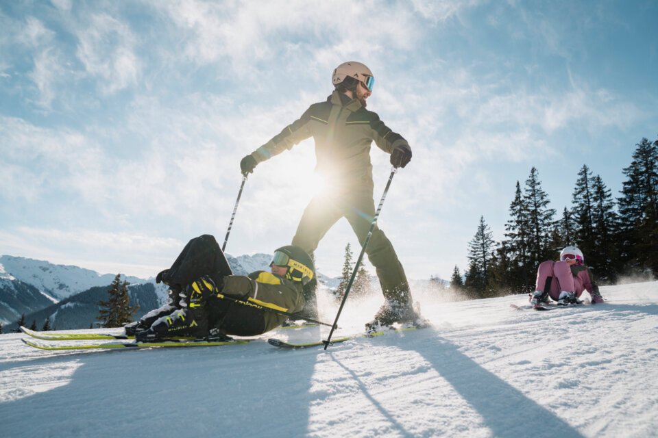 © INTERSPORT International Corporation GmbH Skier falling and being skied over, with child sitting in background. | © INTERSPORT International Corporation GmbH