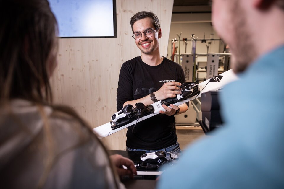 © IIC - INTERSPORT International Corporation GmbH A smiling man wearing glasses holds a ski. | © IIC - INTERSPORT International Corporation GmbH