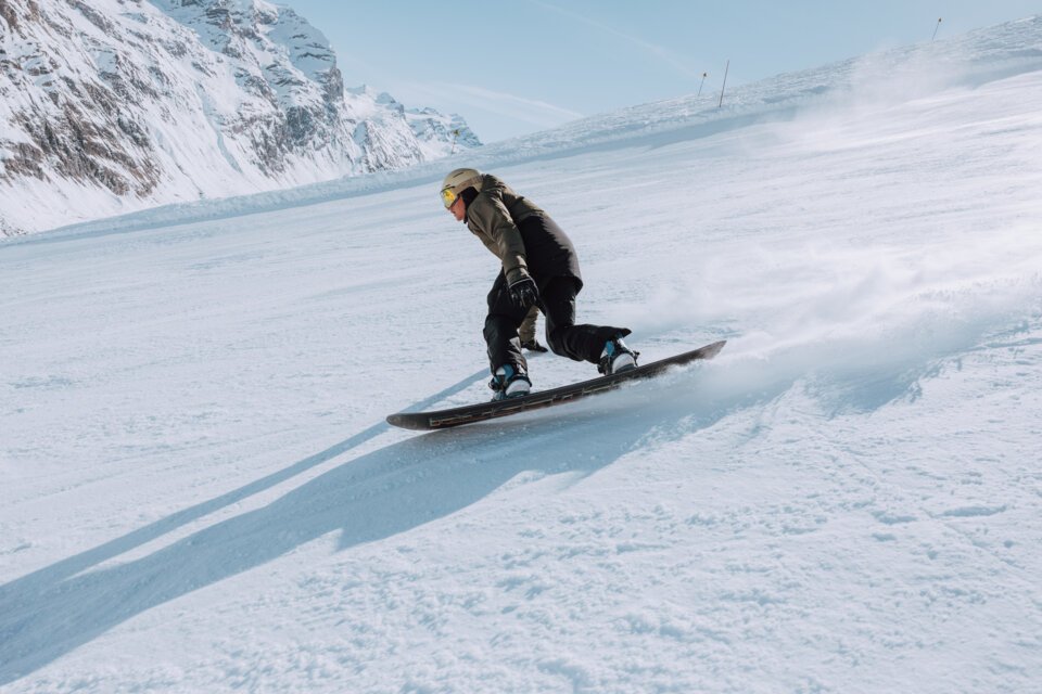 © Oliver Godbold photography / ROSSIGNOL Snowboarder riding down a snowy slope. | © Oliver Godbold photography / ROSSIGNOL