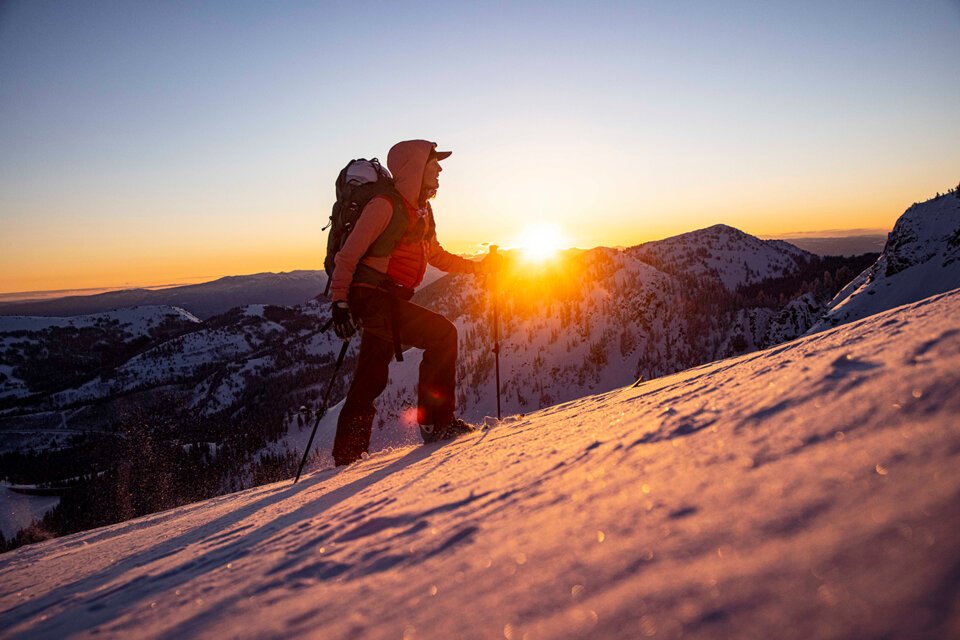 © Salomon Person hiking up a snow-covered mountain at sunrise. | © Salomon