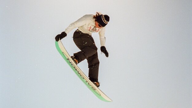 © Salomon Snowboarder in mid-air with mountain backdrop. | © Salomon