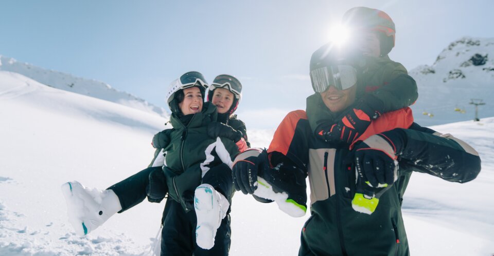 Father carrying two children on his shoulders in the snow.