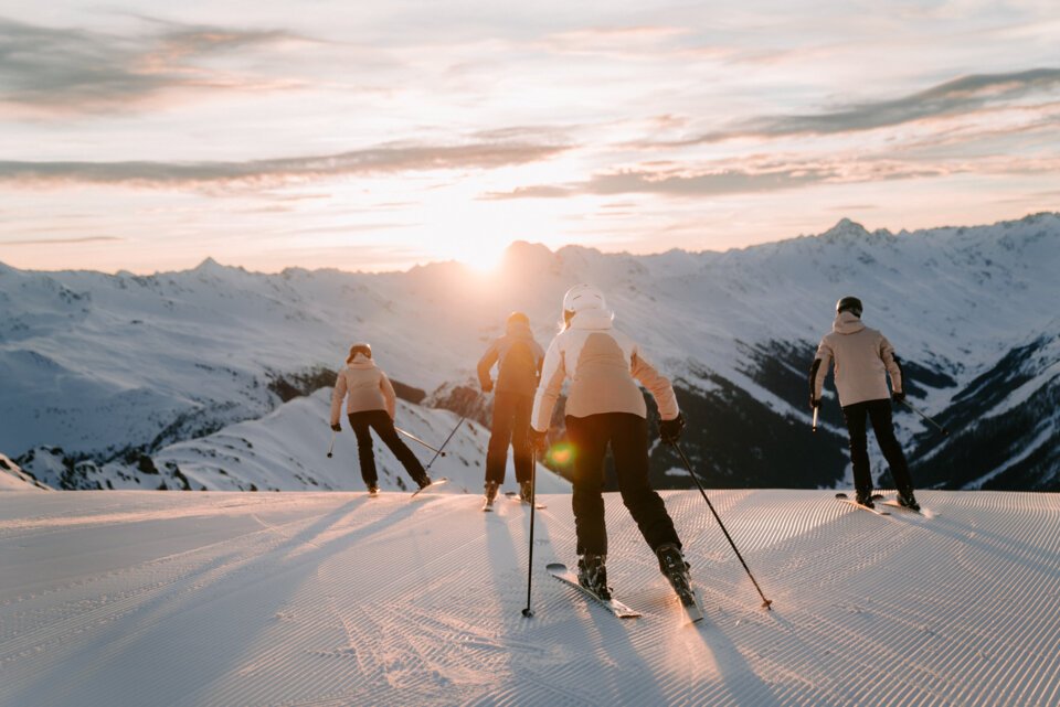 Group of skiers skiing down a mountain at sunset.