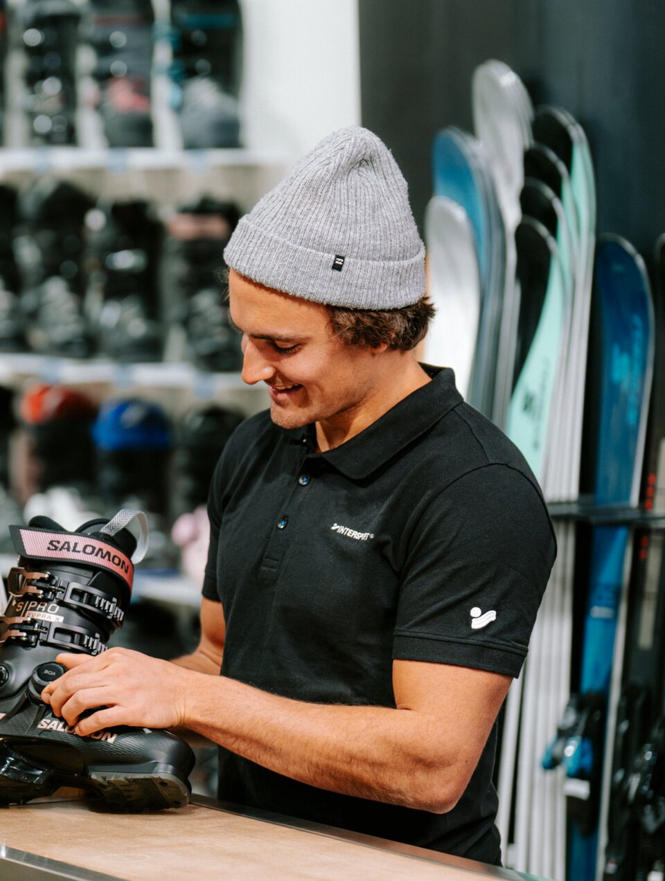 Woman looks approvingly at a sales clerk showing her ski boots.