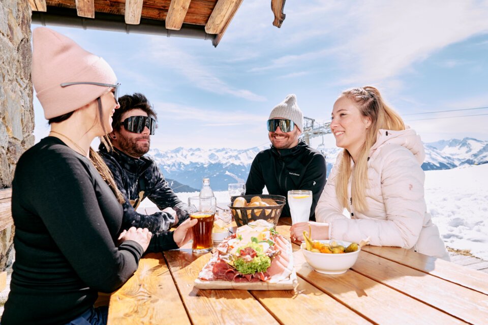 © ARMIN WALCHER Group of friends eating at a ski lodge. | © ARMIN WALCHER